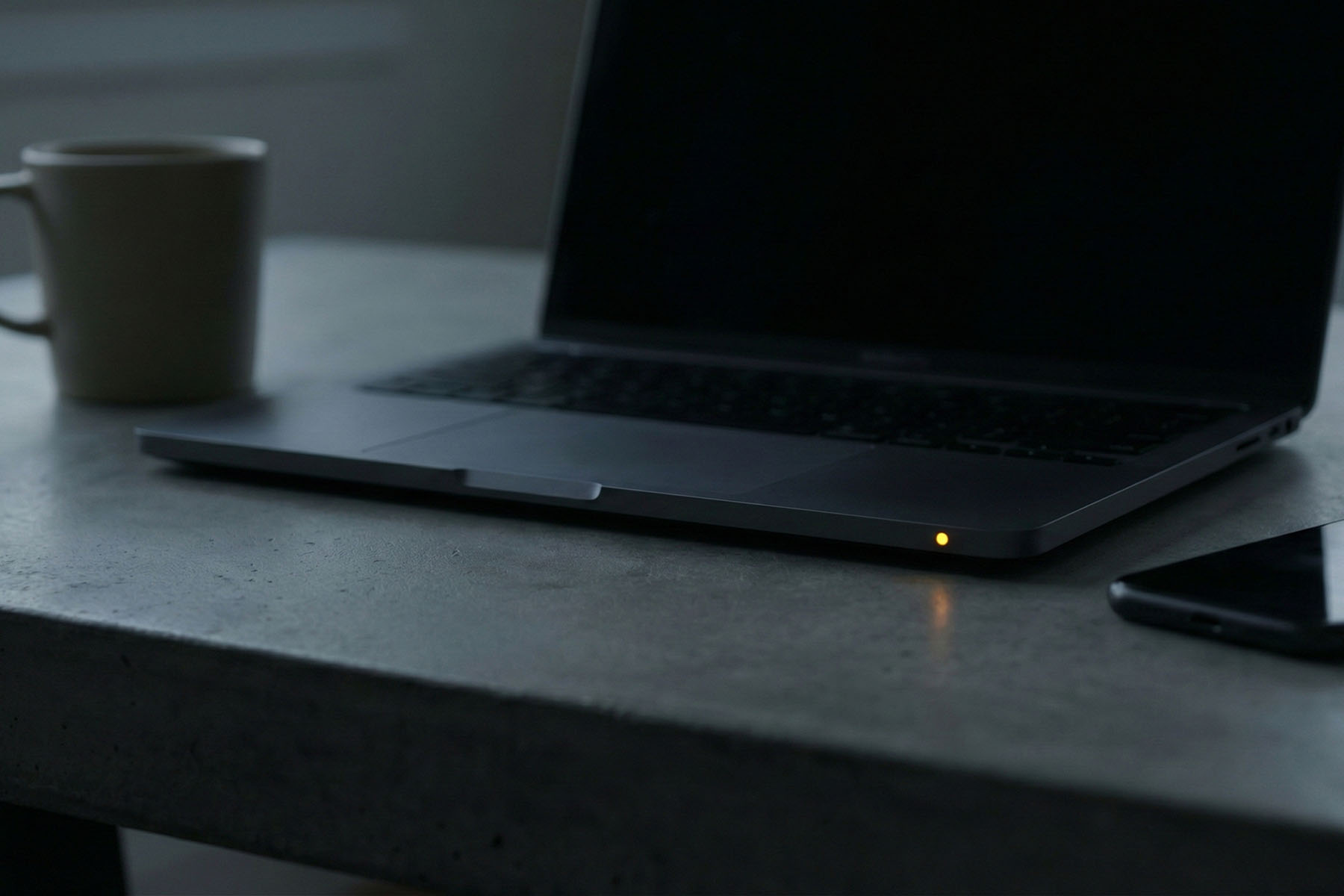 Closed laptop beside coffee mug and phone, representing marketing automation, seo systems, diagnostics, and reporting.