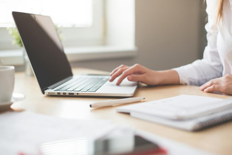 Person typing on laptop at clean desk with notebook and pen nearby for content planning. Image by picjumbo.com (https://www.pexels.com/@picjumbo-com-55570)